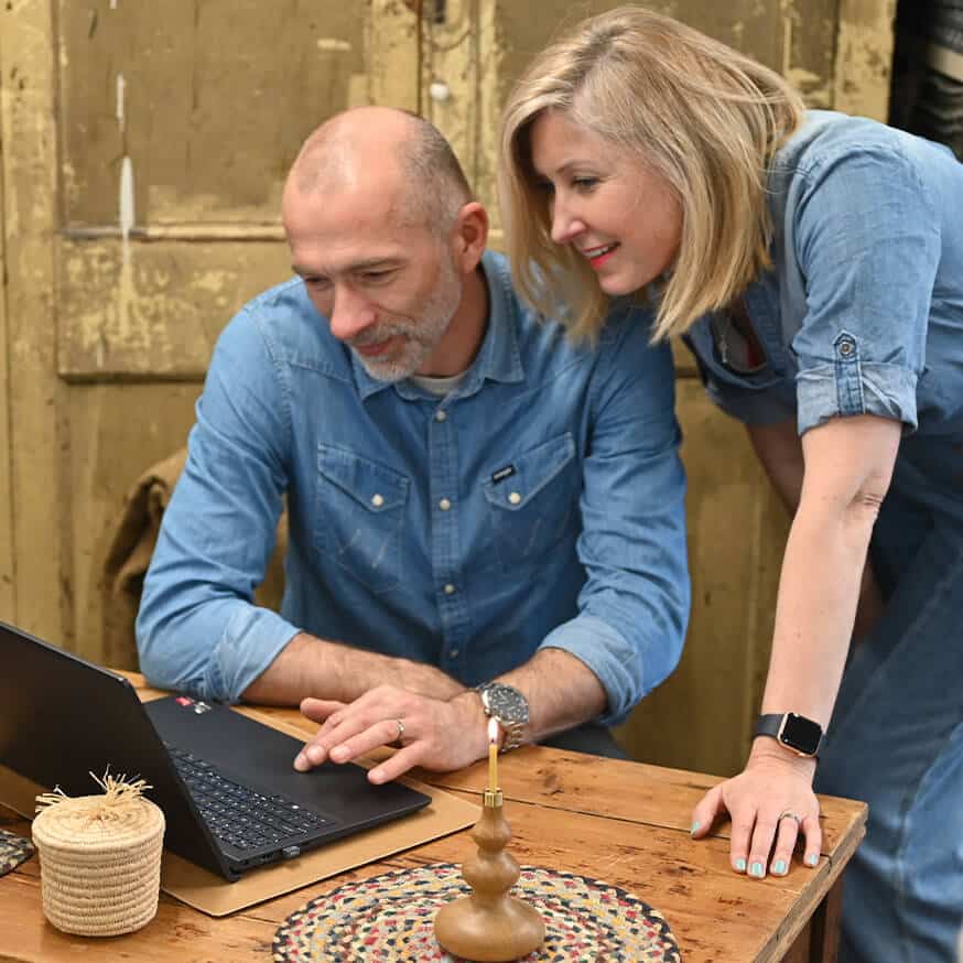 A man and woman with computer on wood table viewing the screen